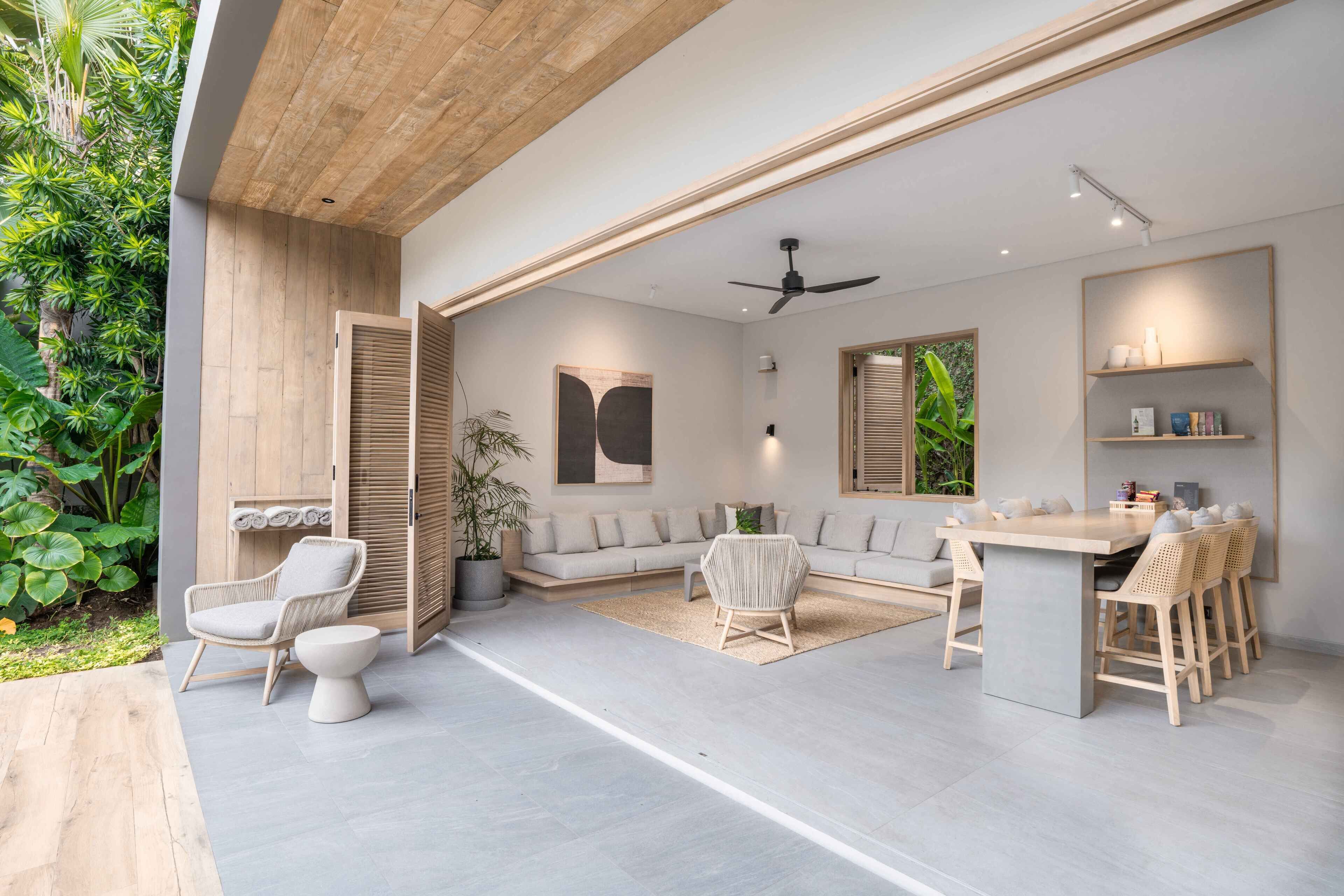 A modern living room with a sofa, chairs, a dining area, and a ceiling fan.