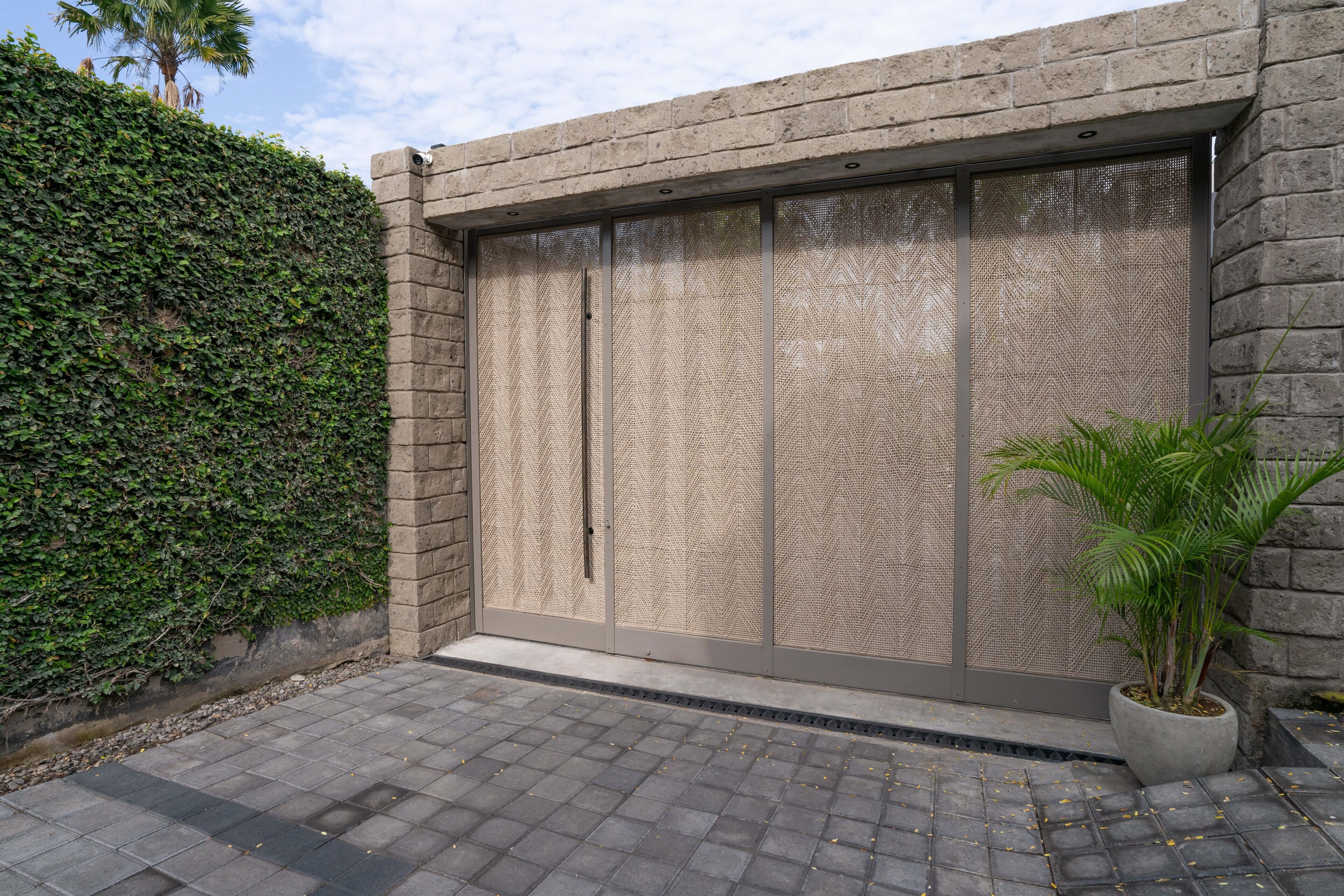 Un bâtiment moderne doté d’un grand portail de garage, d’une plante en pot et d’une allée pavée.