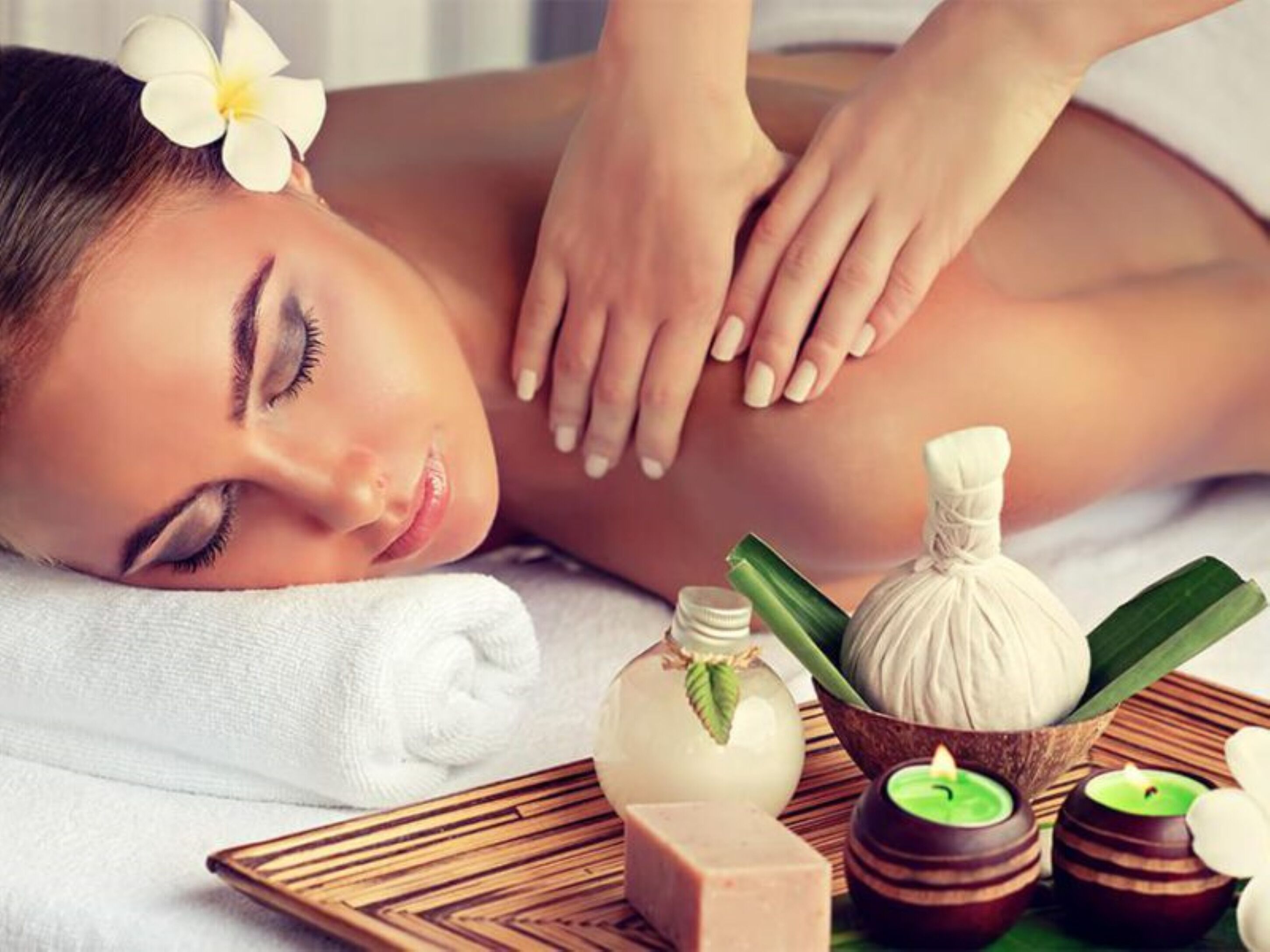 Een wellnessruimte met een massagetafel, een handdoek en diverse spa-producten zoals kaarsen en essentiële oliën.