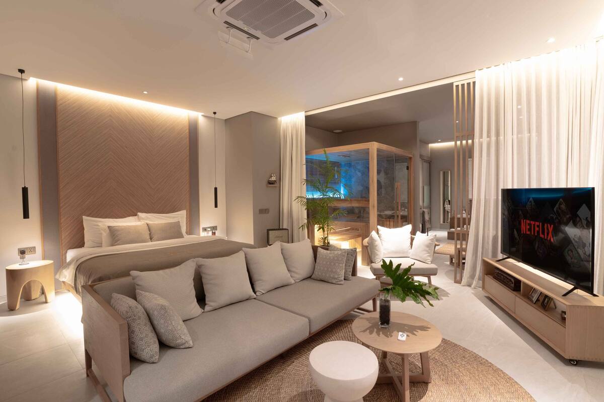A modern living room with a sofa, TV, and a small table with a plant.