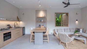 A modern kitchen with a dining area, a sofa, and a coffee table.