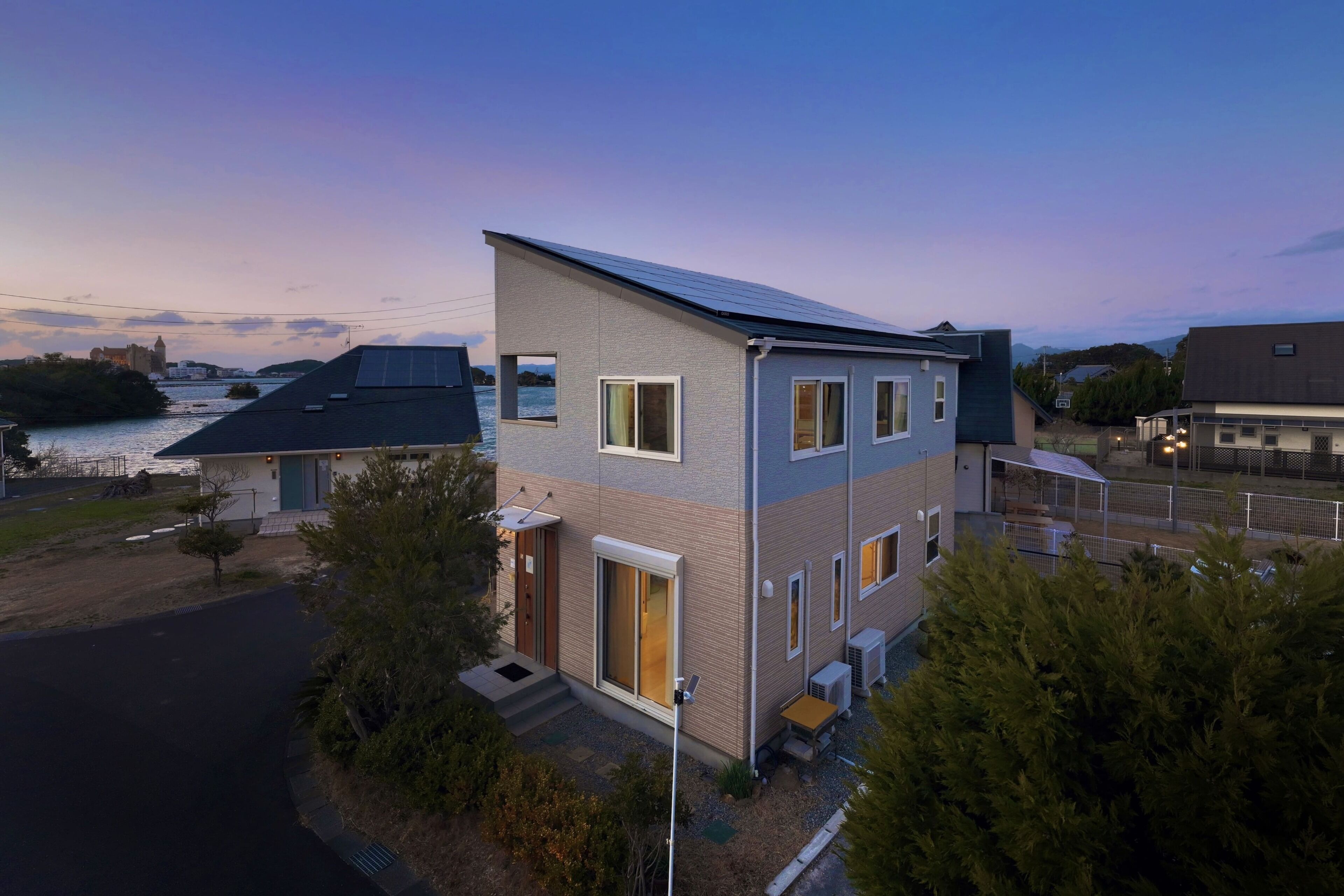 A modern two-story house with a sloped roof, large windows, and a small porch.