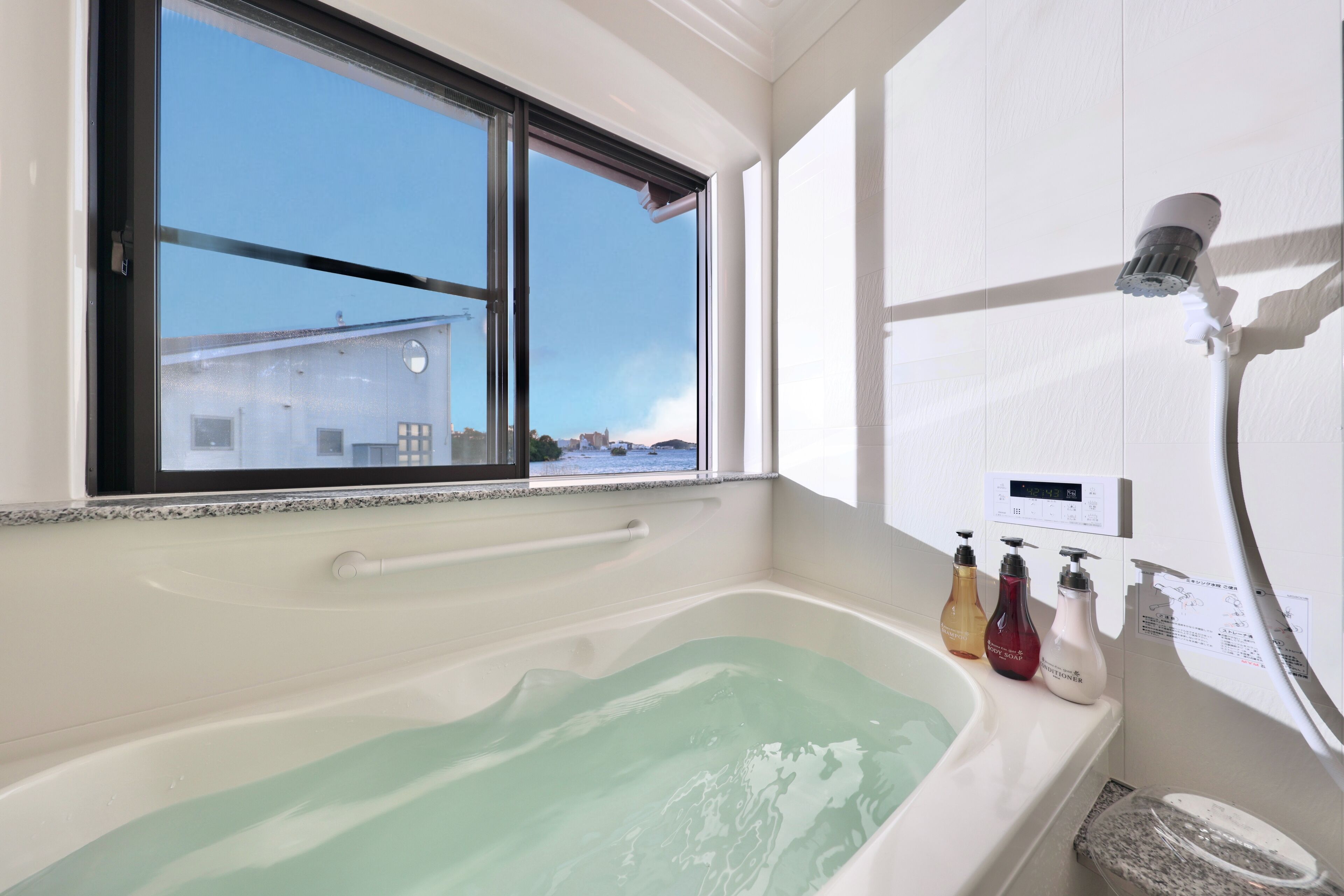 A bathroom with a bathtub, a window, and a showerhead.