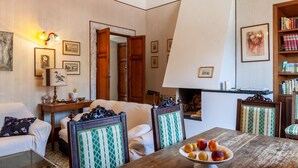 A cozy living room with a fireplace, a dining table with fruit, and a bookshelf. - Apartment 'Palazzo Ricci' with Wi-Fi (Carrara)