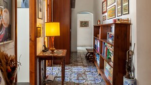 A hallway with a wooden table, a lamp, a bookshelf, and a tiled floor. - Apartment 'Palazzo Ricci' with Wi-Fi (Carrara)