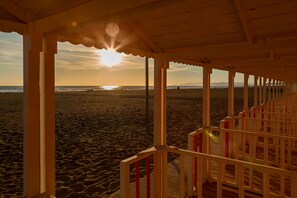 A beach view from a wooden structure with a railing, a clear sky, and the sun setting or rising. - Apartment 'Palazzo Ricci' with Wi-Fi (Carrara)