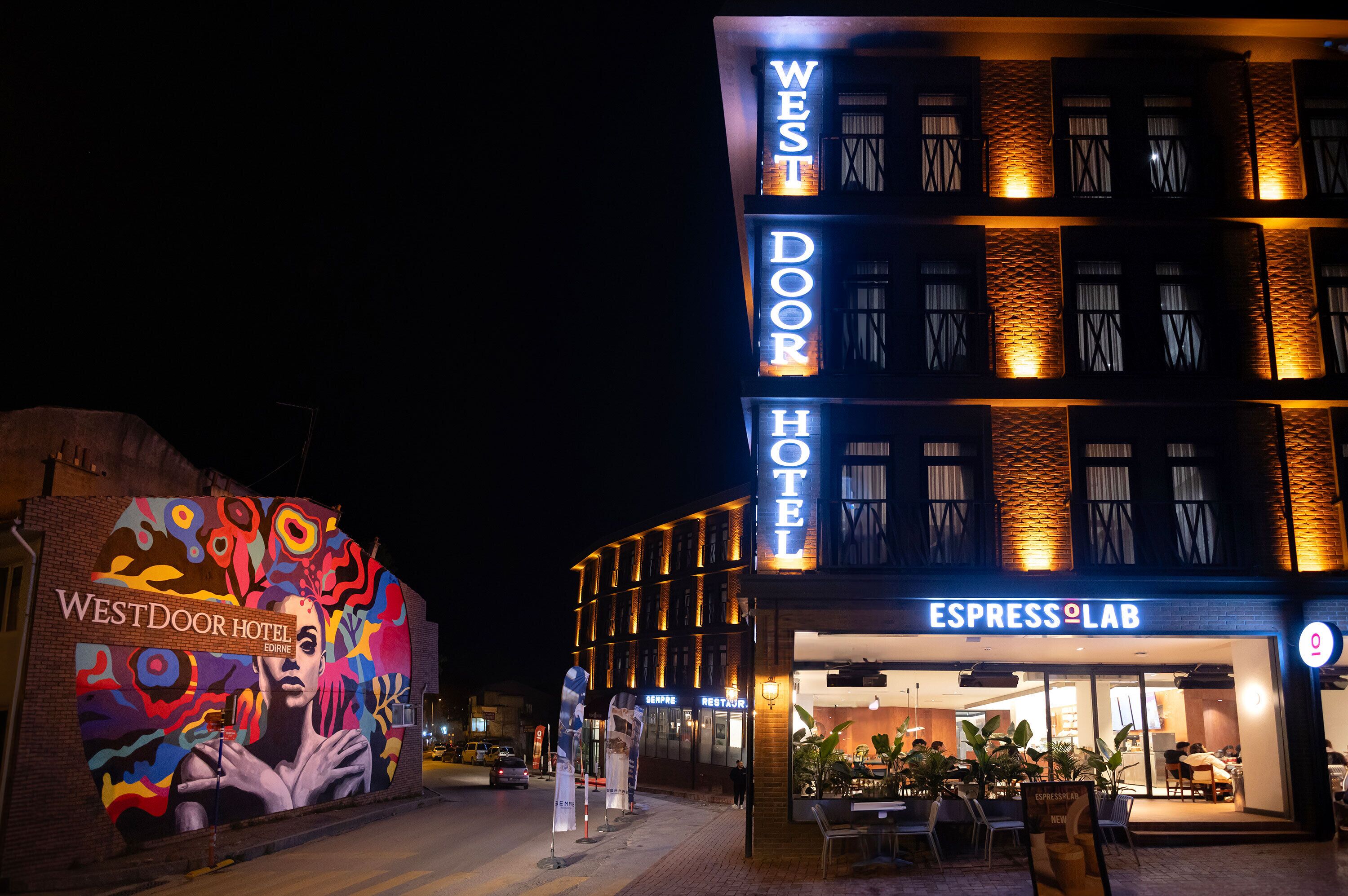 The WestDoor Hotel with a colorful mural on the left, a modern facade, and an Espresso Lab on the ground floor.