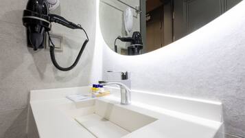 A modern bathroom with a white sink, a hairdryer, and a mirror.