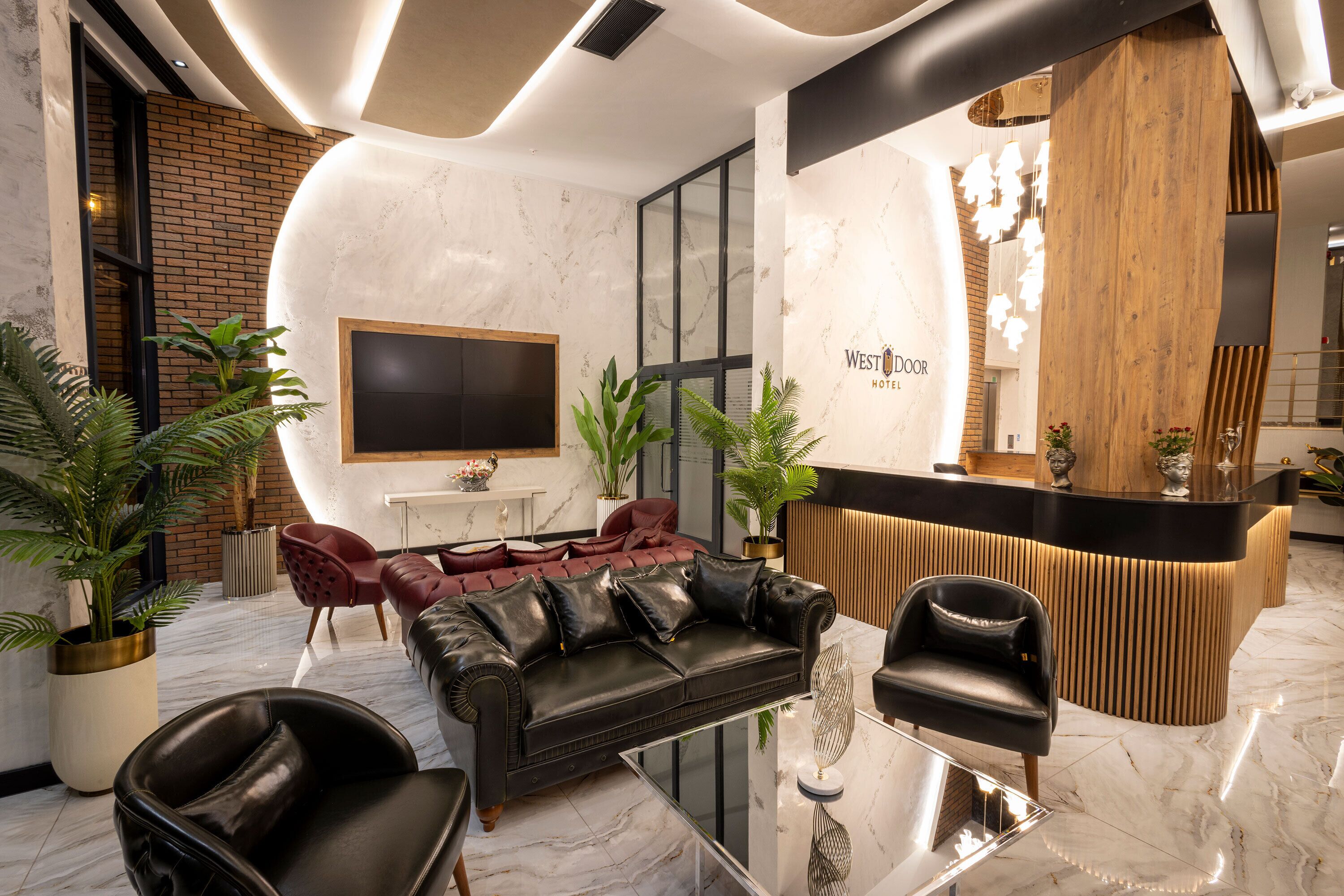 Un vestíbul d'hotel modern amb una recepció, un sofà de cuir i plantes en testos.