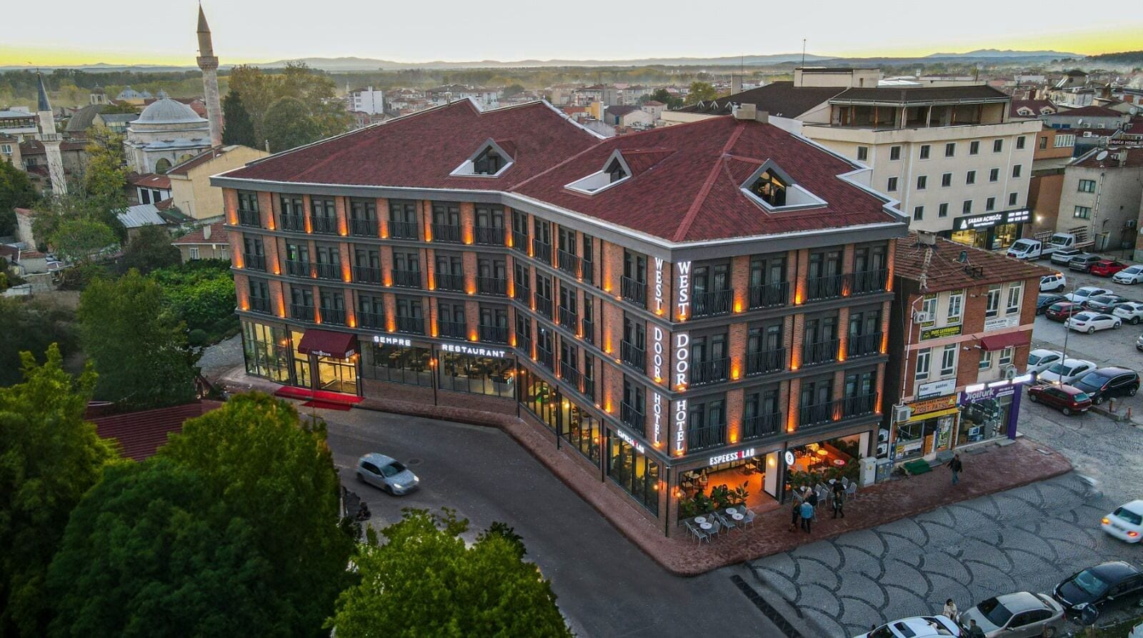 A hotel with a modern design, featuring a prominent entrance, multiple balconies, and a rooftop terrace.