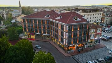 A hotel with a modern design, featuring a prominent entrance, multiple balconies, and a rooftop terrace.