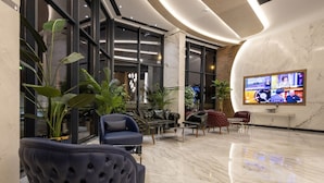 Una hall moderna con pavimento in marmo, divani in pelle e piante in vaso.
