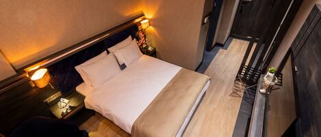 A hotel room with a bed, bedside tables, a chair, and a desk with a lamp.