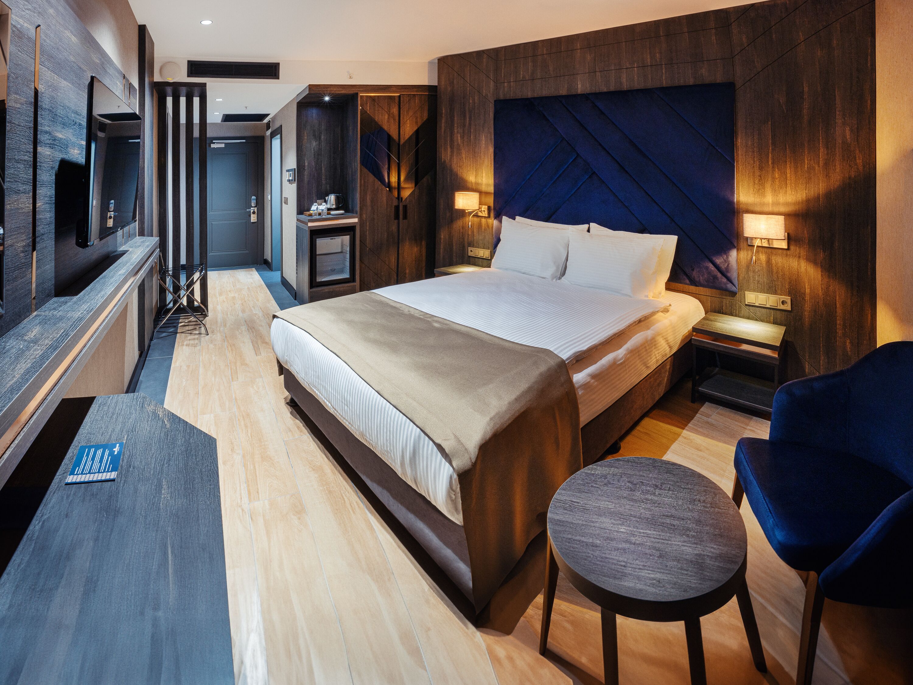 Una habitación de hotel moderna con una cama grande, un escritorio, una silla y un televisor.
