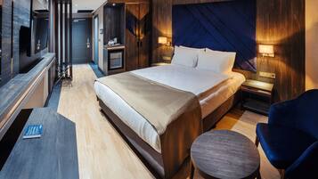 Una habitación de hotel moderna con una cama grande, un escritorio, una silla y un televisor.