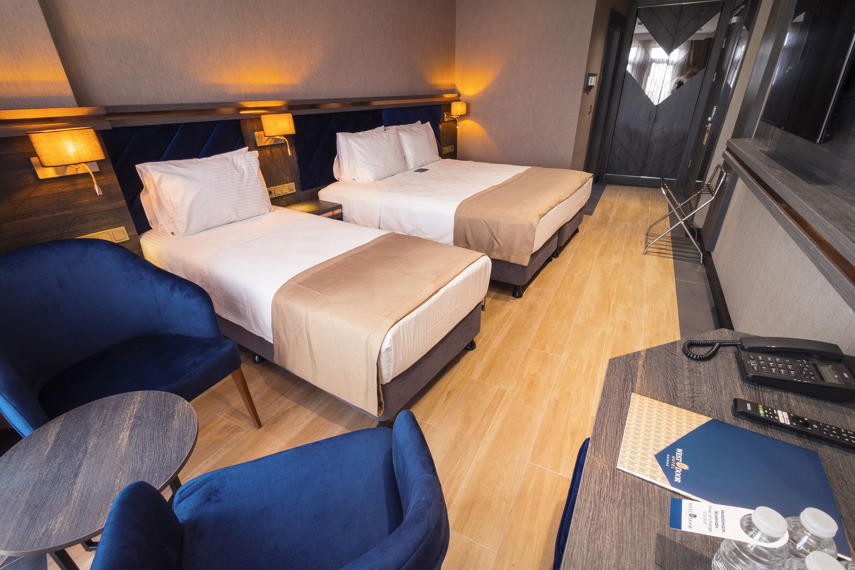 Une chambre d’hôtel avec deux lits, un bureau avec un téléphone et une chaise.