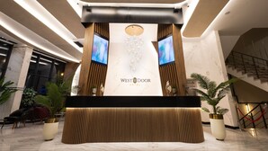 Un'area reception dal design moderno, con scrivania, due monitor e il logo dell'Hotel West Door.