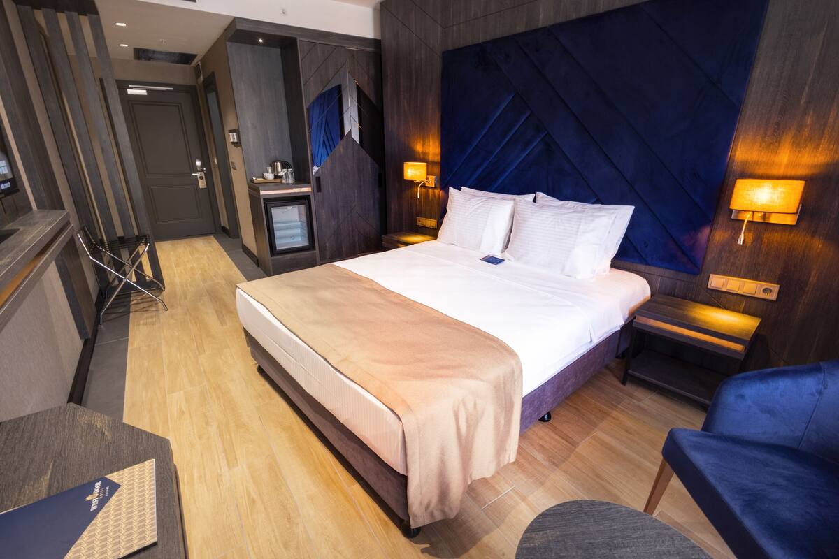 Een moderne hotelkamer met een groot bed, nachtkastjes, een bureau en een stoel.