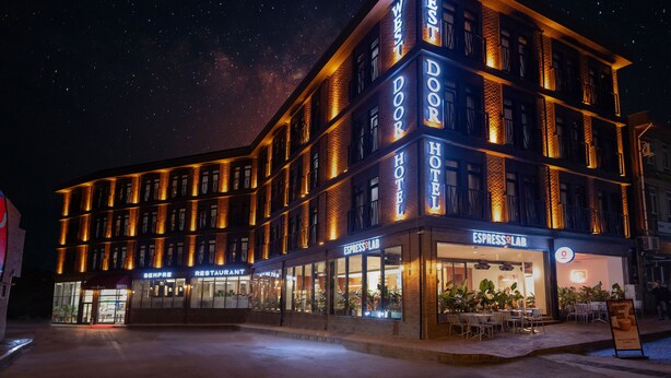 Un hotel a più piani con un'insegna ben visibile del West Door Hotel, una Espresso Lab e un ristorante.