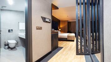 A hotel room with a bathroom, a bed, and a wooden partition.