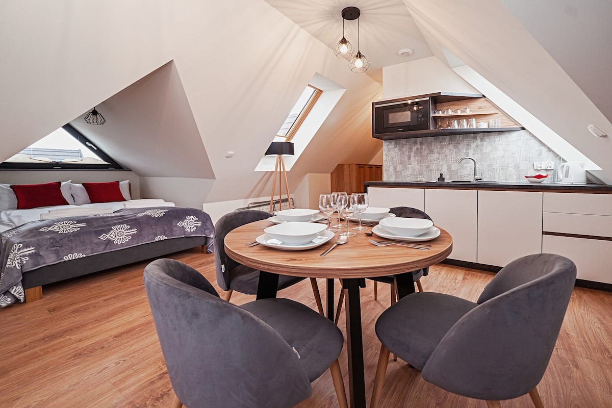 Ein kompakter, moderner Loft mit Essbereich, Küche und Schlafgelegenheiten.