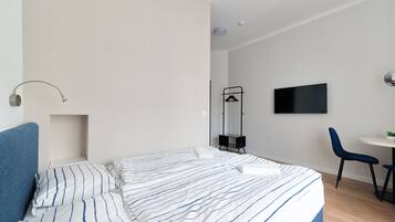 Ein modernes Hotelzimmer mit Bett, Schreibtisch, Sessel und Fernseher.
