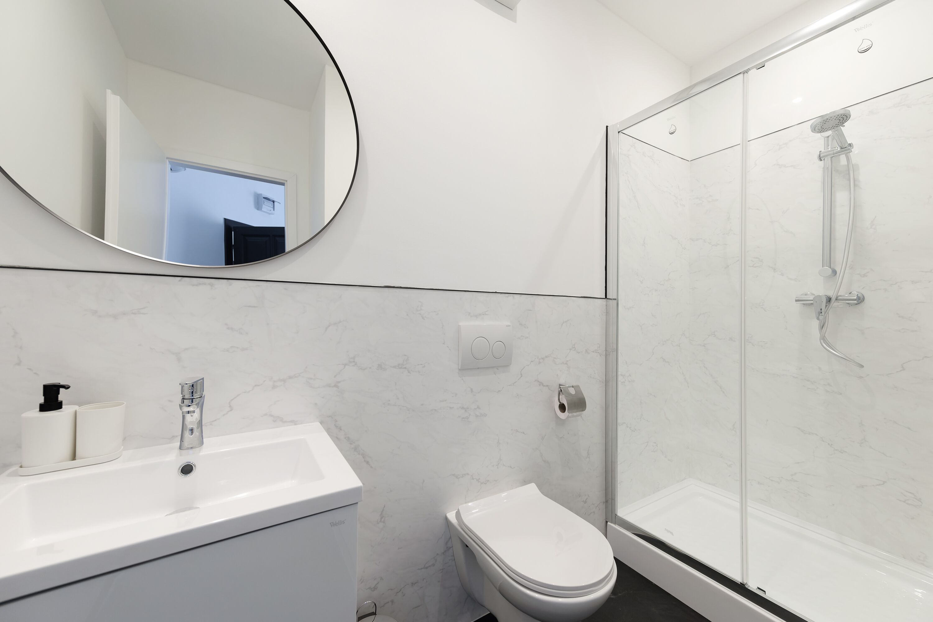 Un bagno con lavandino bianco, water e doccia con pareti in vetro.