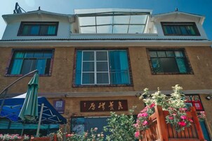 Un edificio de dos pisos con un gran ventanal en el segundo nivel, un letrero con caracteres chinos y una jardinera en la fachada.