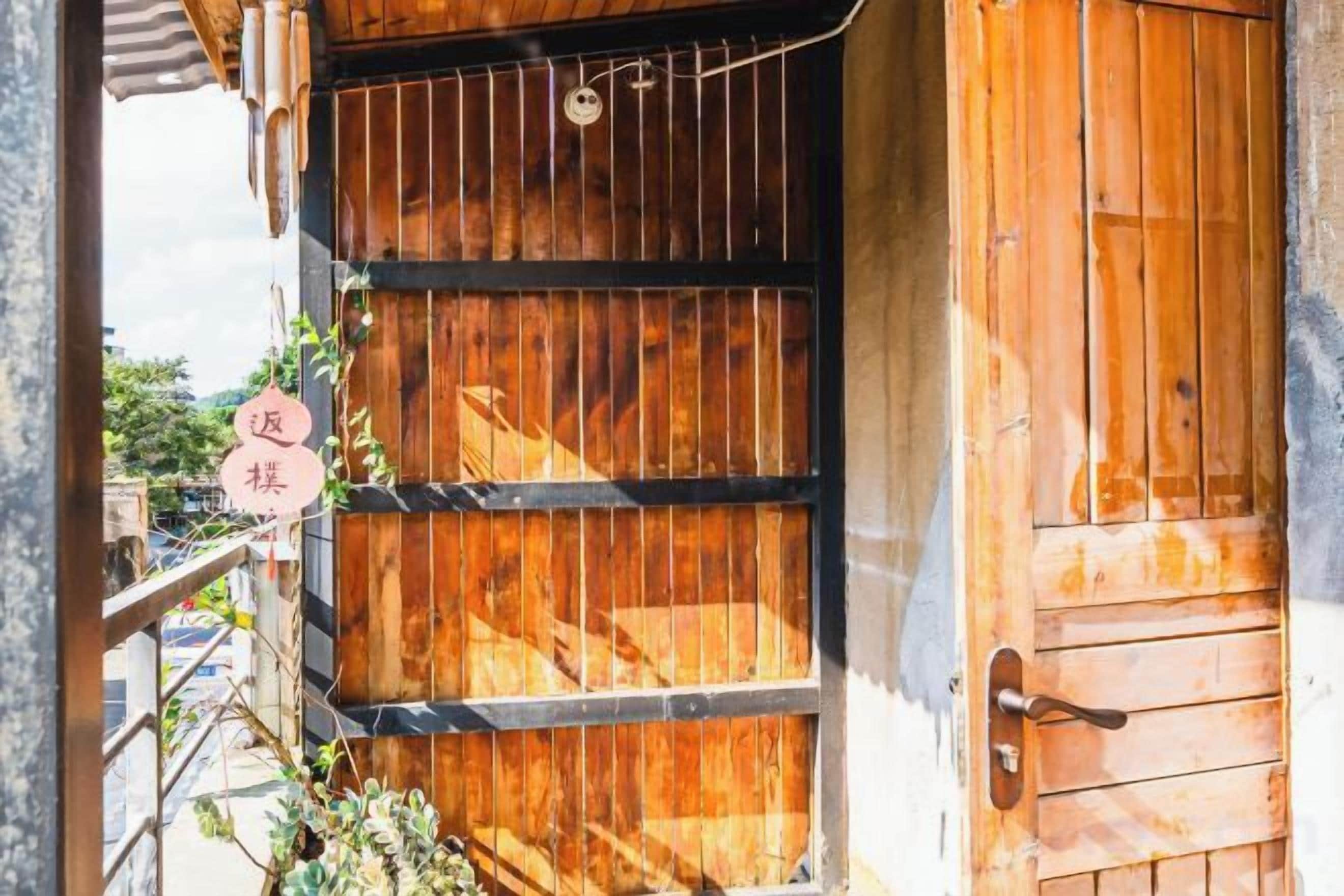 A wooden door with a metal latch and a sign with Japanese characters.