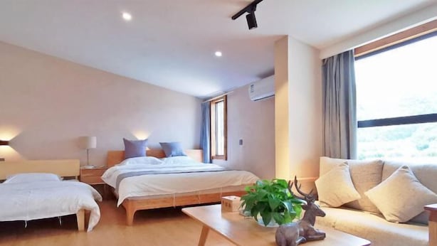 Una habitación de hotel moderna con cama, sofá, mesa de centro y ventana con cortinas.