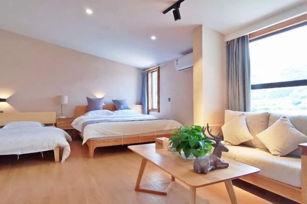 A modern hotel room with a bed, a sofa, a coffee table, and a window with curtains.
