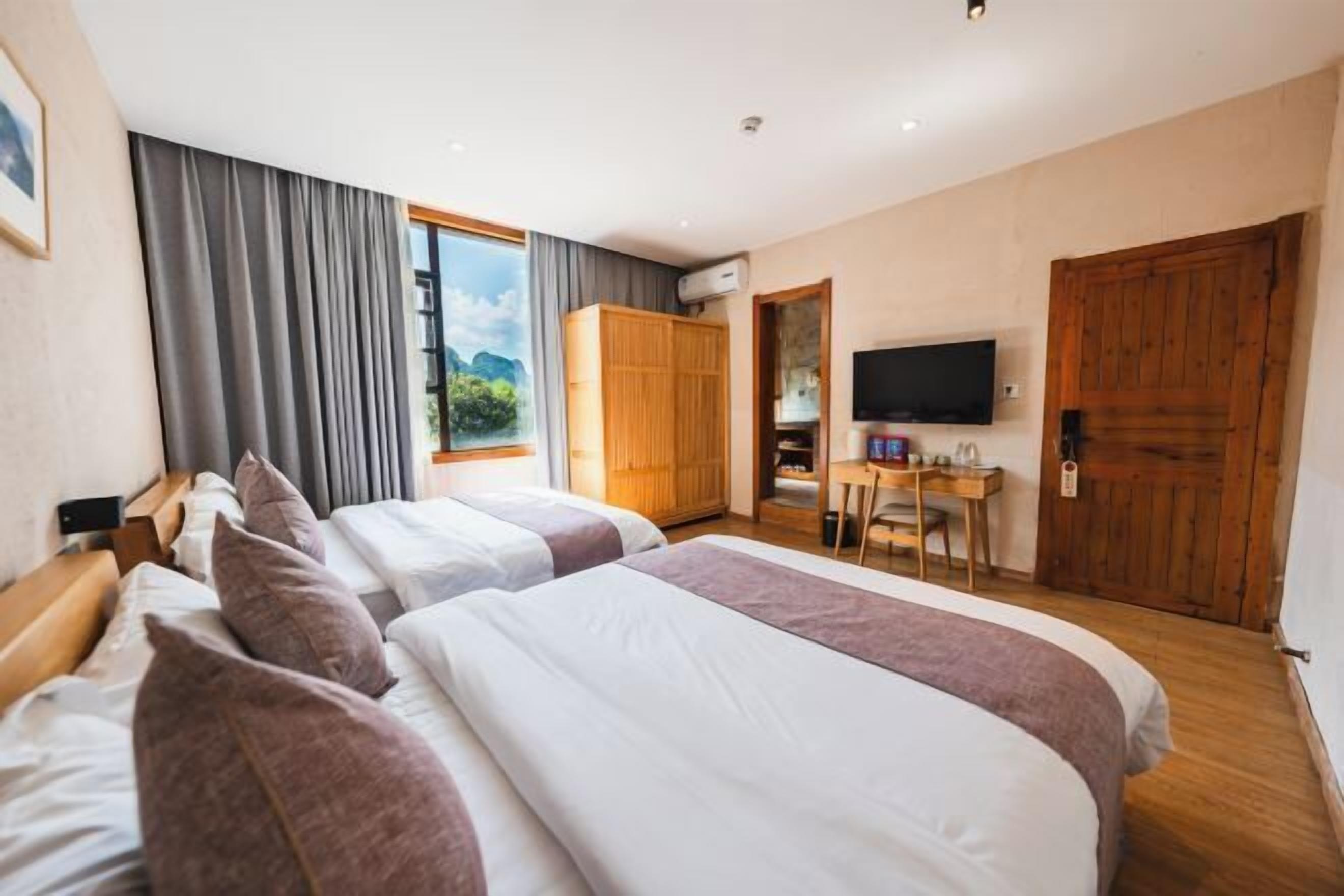 Une chambre d’hôtel avec deux lits, un bureau, une télévision et une armoire.