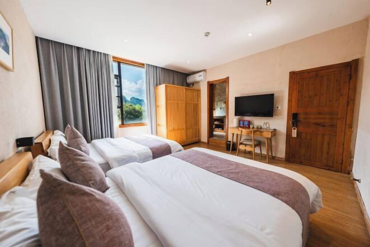 A hotel room with two beds, a desk, a TV, and a wardrobe.
