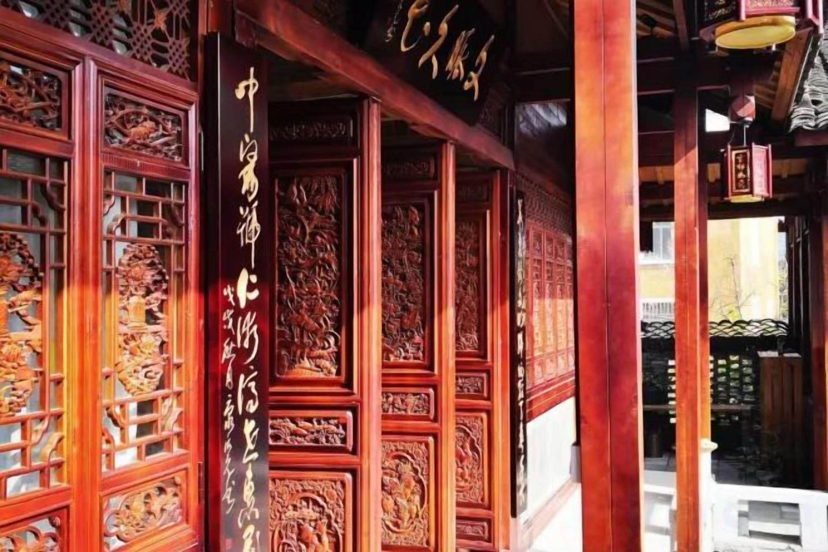 Una estructura de madera tradicional con elaboradas tallas y un letrero con caracteres chinos.