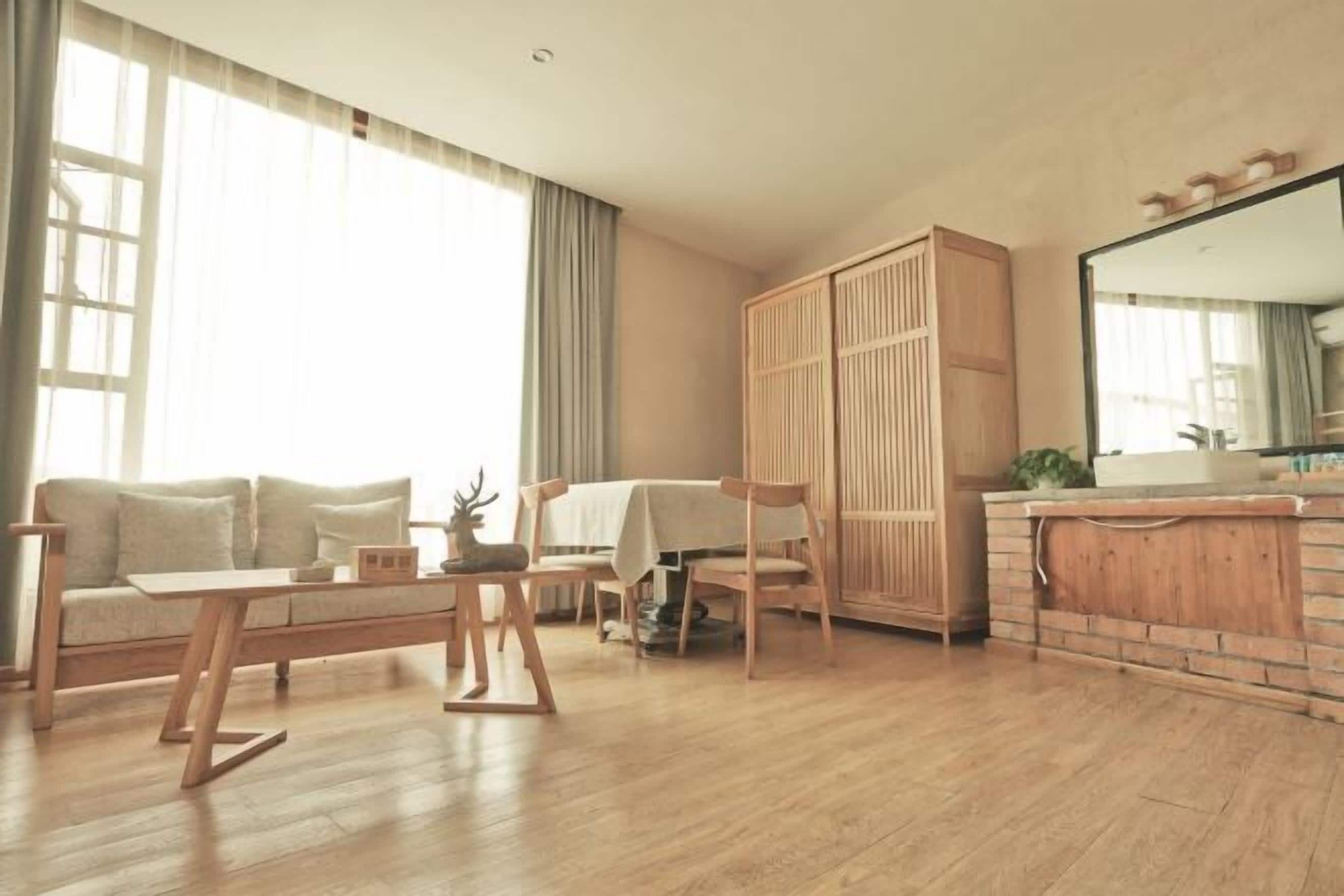 Una sala moderna con sofá, una mesa de centro, una mesa de comedor con sillas, un armario de madera y una zona de cocina con fregadero y encimera.