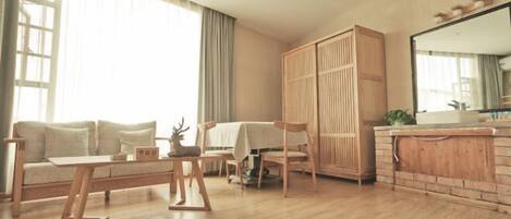 Una sala moderna con sofá, una mesa de centro, una mesa de comedor con sillas, un armario de madera y una zona de cocina con fregadero y encimera.