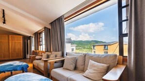Una habitación acogedora con sofá, una mesita y vistas a las montañas a través de amplias ventanas.