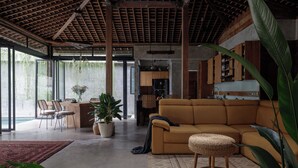 A spacious living area with a large sofa, a dining table with chairs, and a kitchen area with wooden cabinets. - Pritidaya Private Pool Villa Canggu by OXO (Canggu)