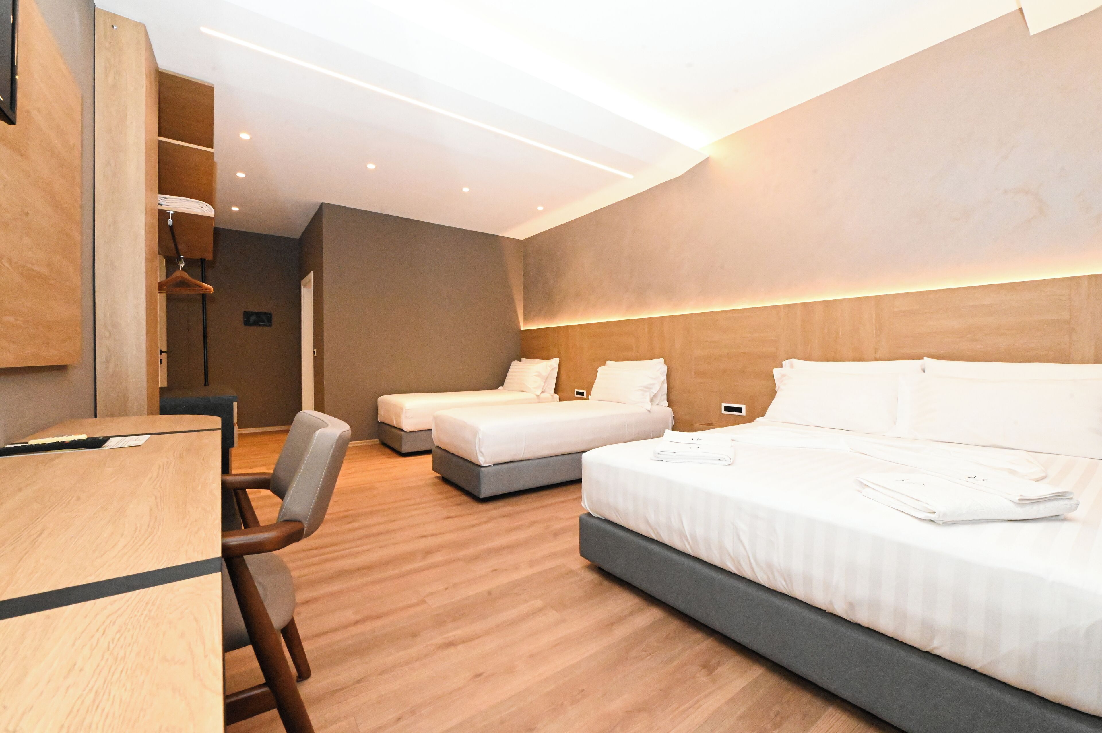 A modern hotel room with a large bed, a smaller bed, and a desk with a chair.