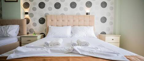 Une chambre d’hôtel avec un grand lit, deux tables de chevet et une tête de lit.