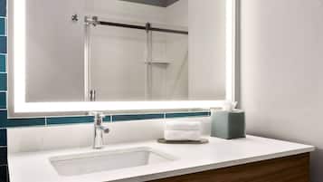 A bathroom with a large mirror, a sink, and a towel dispenser.