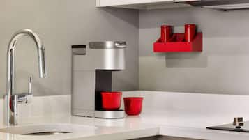 A modern kitchen with a stainless steel sink, a coffee maker, and red cups on the counter.