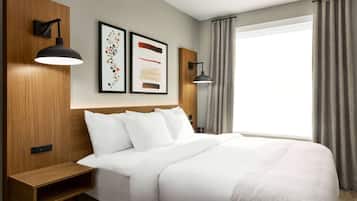 Habitación de hotel con una cama grande, dos lámparas de lectura fijadas a la pared y un ventanal con cortinas.