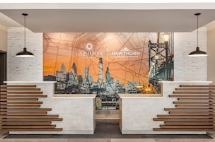 Un área de recepción con un mural de la ciudad, listones de madera e iluminación colgante.
