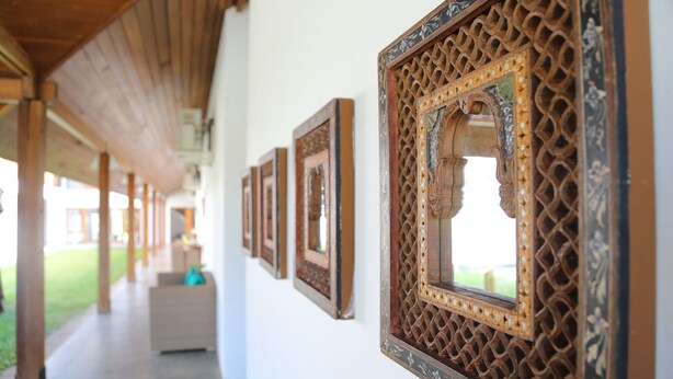 A corridor with wooden beams and framed artwork on the walls.