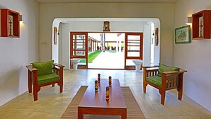 A spacious room with two wooden chairs and a table, a large mirror, and a view through an open doorway to an outdoor area.