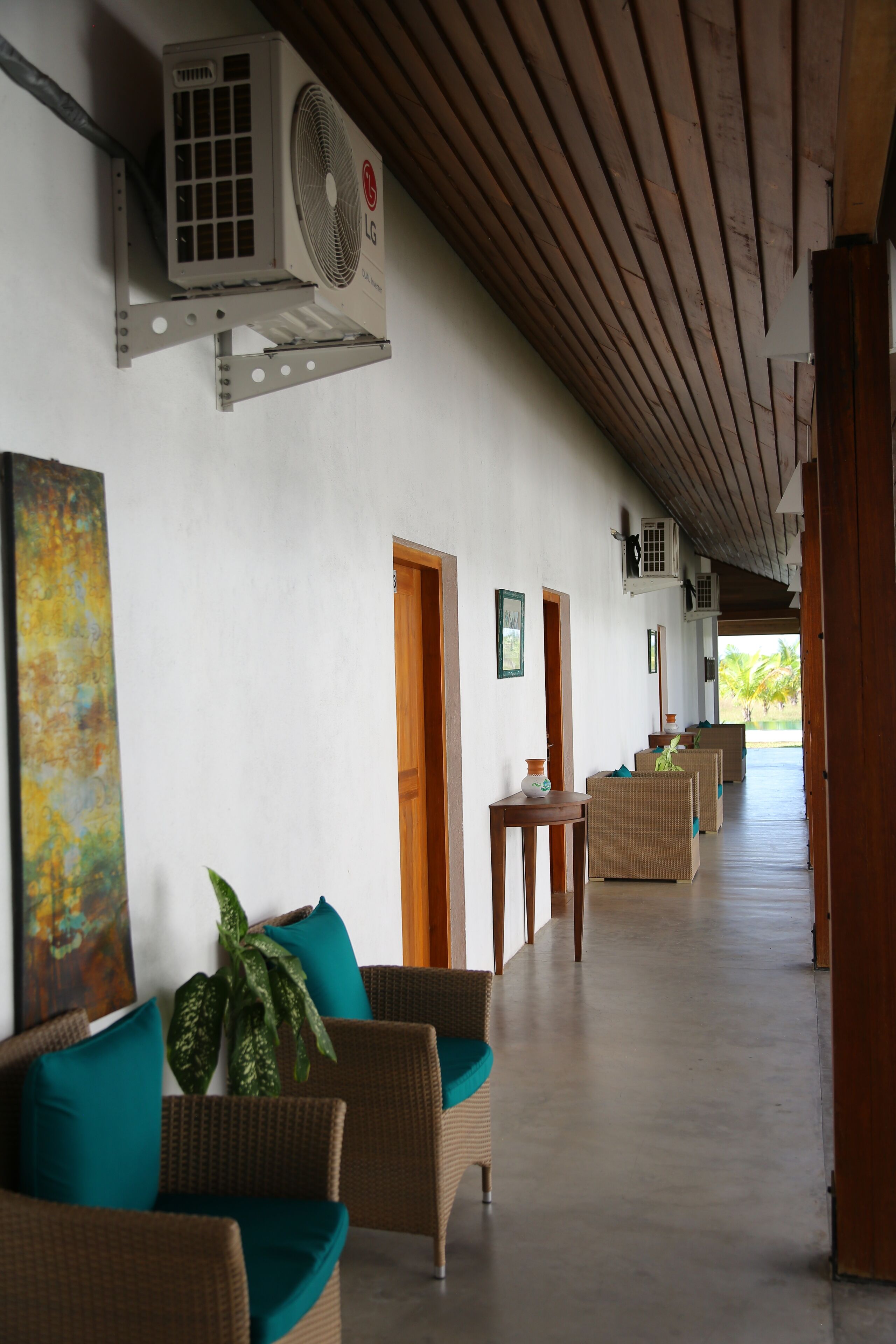 A corridor with wicker furniture, a ceiling fan, and an air conditioning unit.