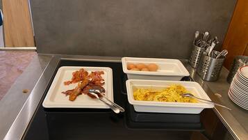 Un buffet de petit-déjeuner avec du bacon, des œufs et des œufs brouillés.