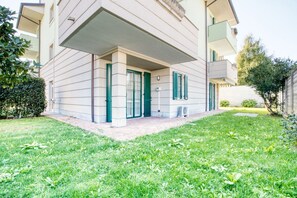 Un bâtiment moderne à deux étages, doté d’une entrée couverte, d’un petit jardin et d’un appareil de climatisation visible.