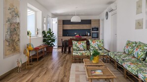 Ein modernes Wohnzimmer mit Holzboden, einer Couch, einem Couchtisch und einem Essbereich mit Stühlen und einem Tisch.